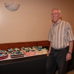 Past Executive Director standing by cake letters that spell his name.